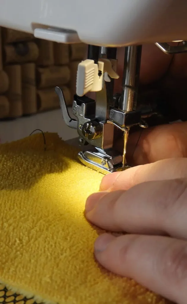 Une personne qui coud une éponge jaune avec une machine à coudre.
